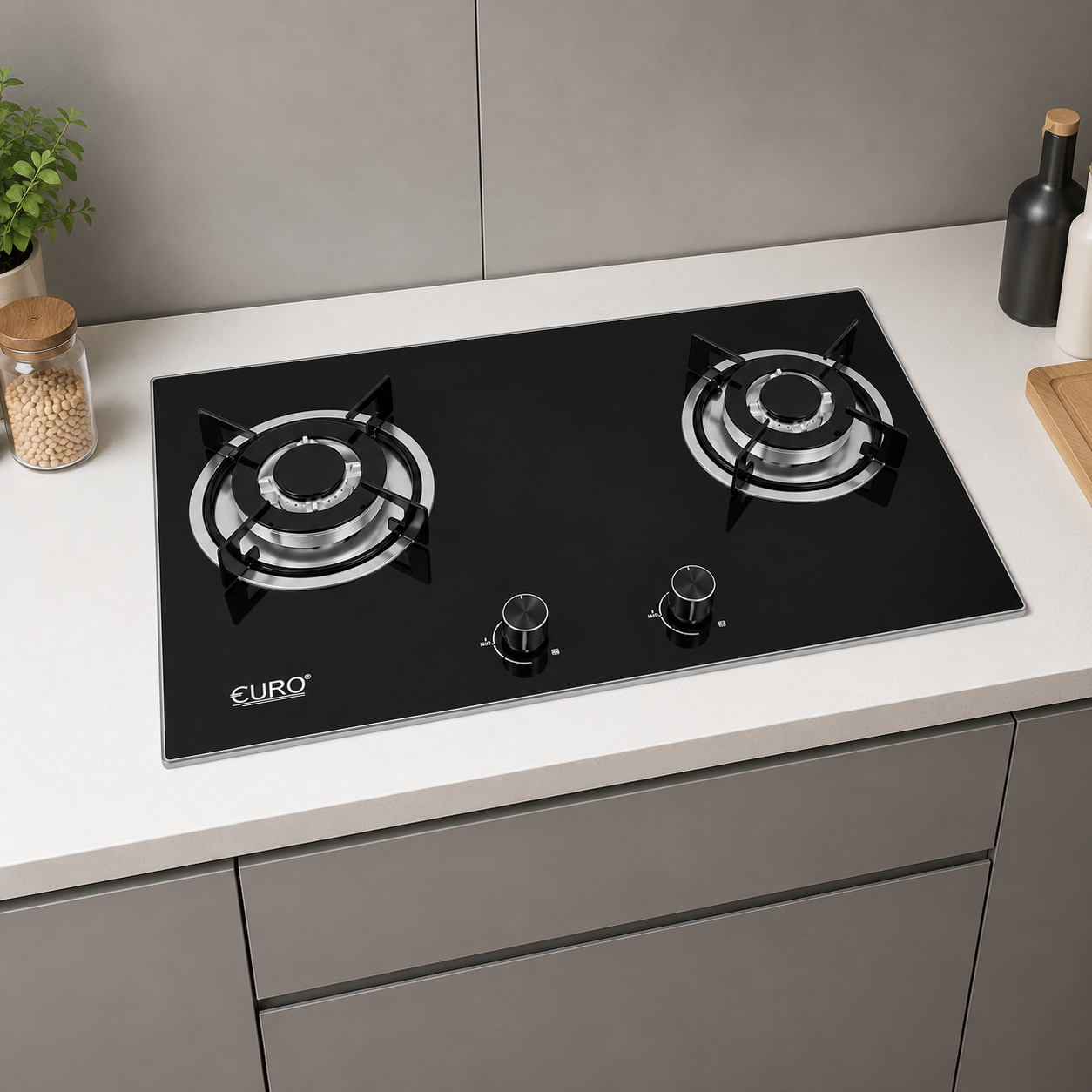 A black glass-top two-burner gas stove with silver burner grates and two silver control knobs, installed on a white kitchen countertop with gray cabinets and backsplash.