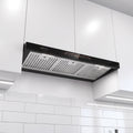 A black and stainless steel kitchen range hood mounted under white cabinets above white subway tiles.