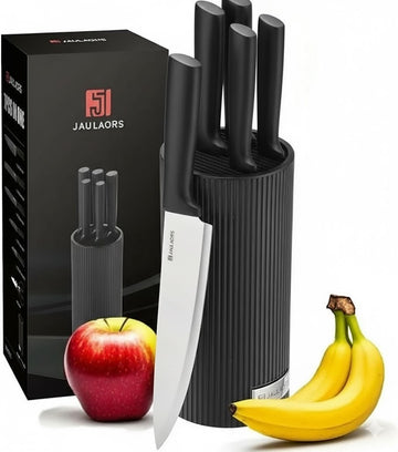Set of black knives in a holder with a Jaulaors box, apple, and bananas on a white background
