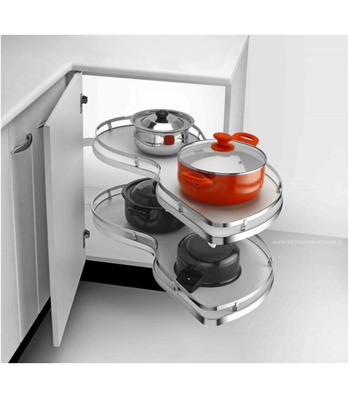 A stainless steel corner cabinet organizer with multiple shelves, containing pots and a cutting board, installed in a white kitchen cabinet.