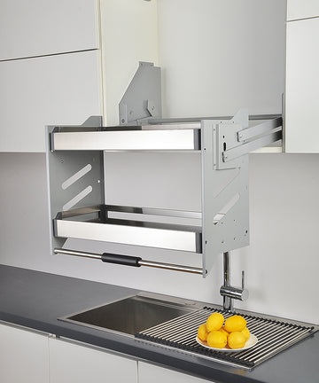 A stainless steel Kangyale elevator basket mounted on a wall above a kitchen sink, partially open with some kitchen towels inside.