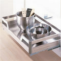 Stainless steel kitchen drawer organizer with pots and utensils on a light wood floor.