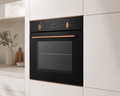 Modern kitchen with a black oven featuring copper handles and trim.